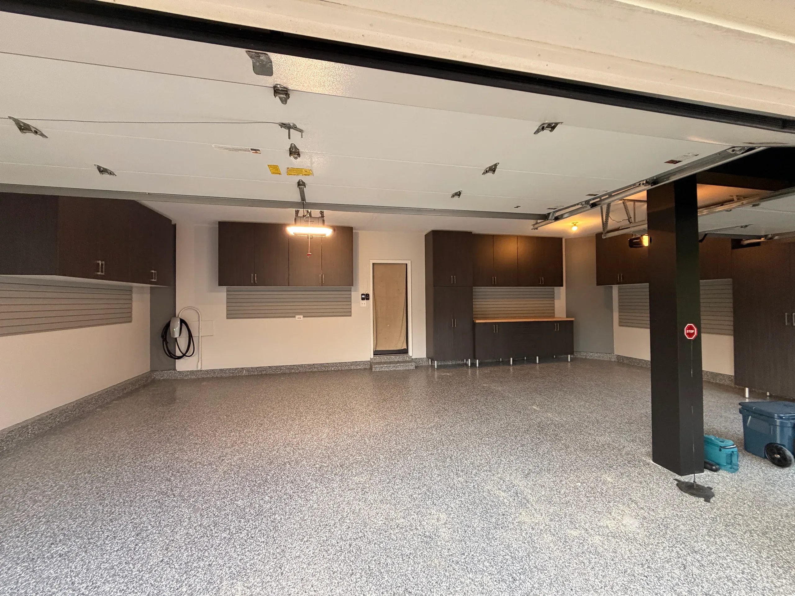 Two-car garage with dark walnut cabinets along two walls, slatwall panels and epoxy floor