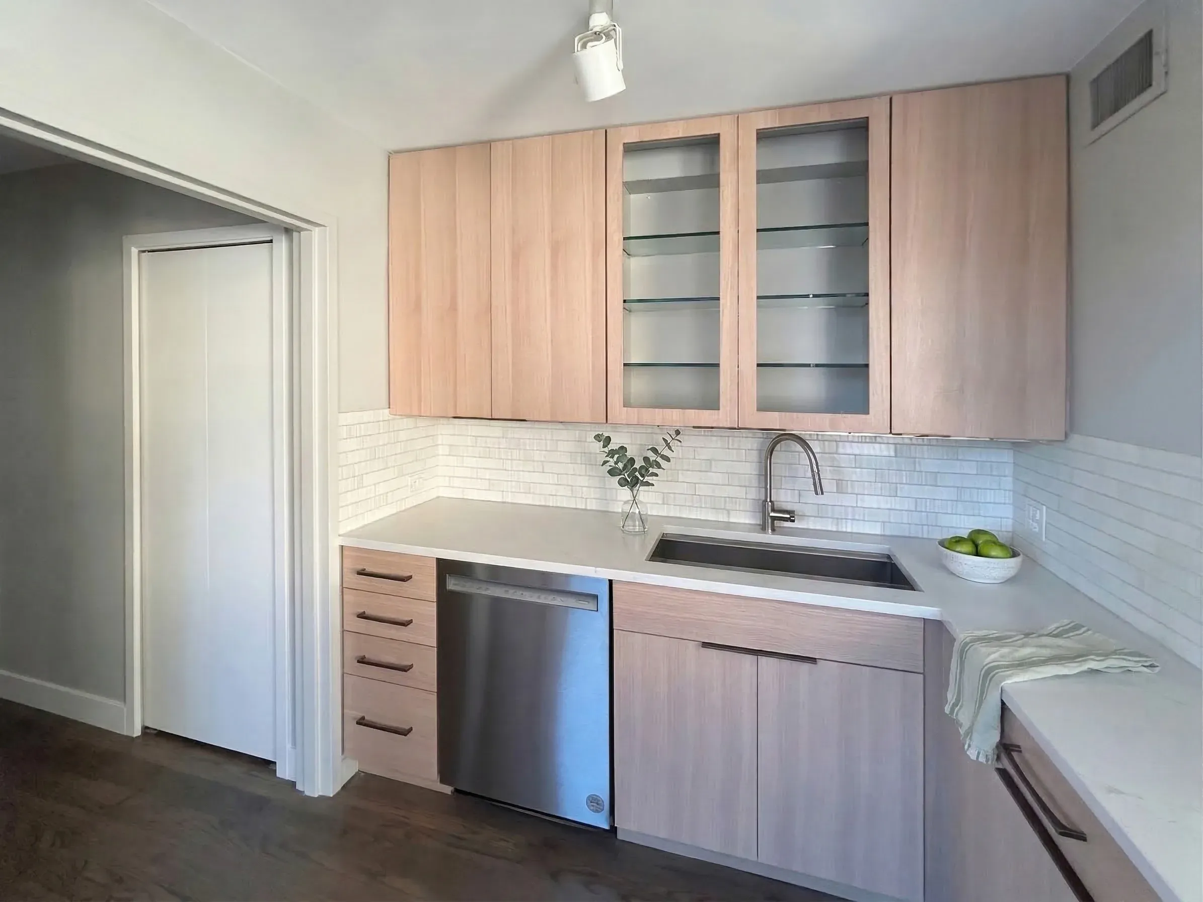 Refaced kitchen with white oak slab fronts, glass-front upper cabinets and white quartz countertops
